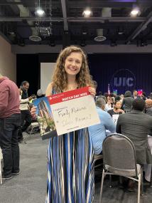 Megan Helms in an event space holding a sign stating she matched into family medicine at Illinois Masonic